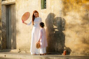A woman and child in traditional Ao Dai dresses on a sunny day in Hội An, Vietnam.