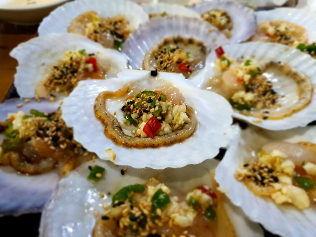 Freshly prepared grilled scallops garnished with colorful seasoning and herbs.